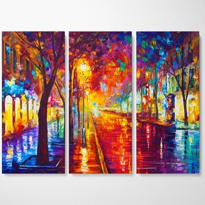 May include: A vibrant, multi-panel canvas art piece depicting a colorful street scene at night. The artwork features a wet, reflective street with warm, glowing streetlights and buildings. The color palette includes reds, oranges, blues, and purples, creating a lively atmosphere.