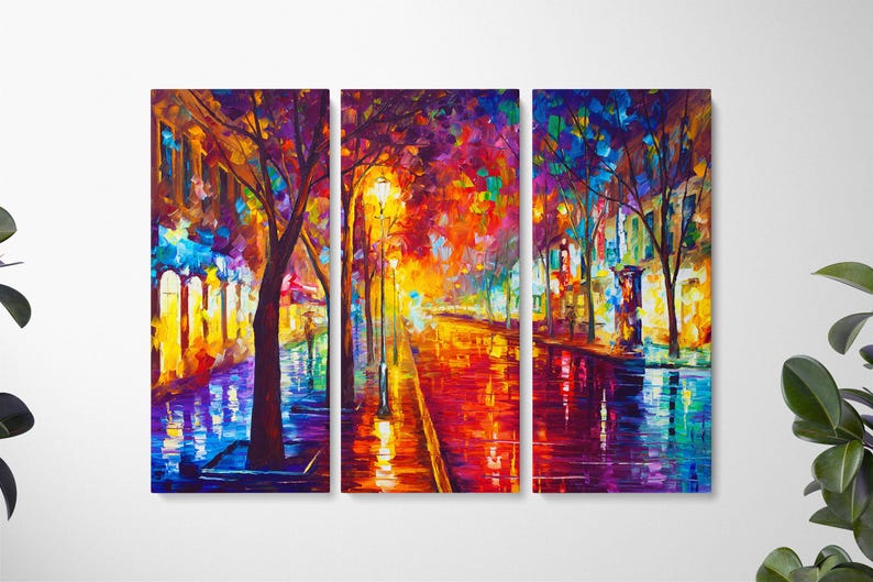 May include: A vibrant, multi-panel canvas art piece depicting a colorful street scene at night. The artwork features a wet, reflective street with warm, glowing streetlights and buildings. The color palette includes reds, oranges, blues, and purples, creating a lively atmosphere.