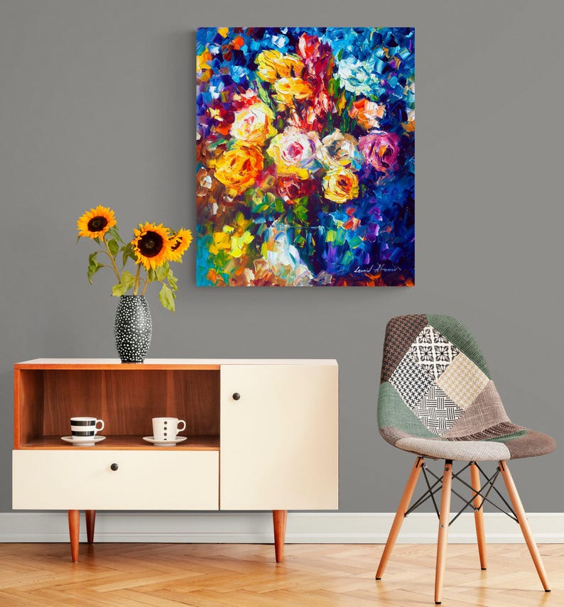 May include: An abstract floral painting with vibrant colors, including yellow, orange, and pink roses, hangs on a gray wall. A modern cabinet with a vase of sunflowers and a patterned chair complete the room's decor.