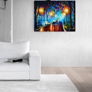 May include: A vibrant oil painting depicts a couple walking on a wet path in a park, illuminated by streetlights. The artwork features a colorful palette of blues, oranges, and yellows, with benches lining the path. The painting is displayed on a white wall above a white sofa.