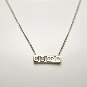 Puede incluir: Un collar de cadena de plata con un colgante rectangular engastado con pequeños diamantes redondos y baguette.