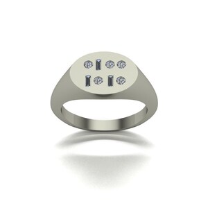 Pu&ograve; includere: Un anello a sigillo d'argento con una parte superiore ovale piatta incastonata con piccoli diamanti in un motivo geometrico.