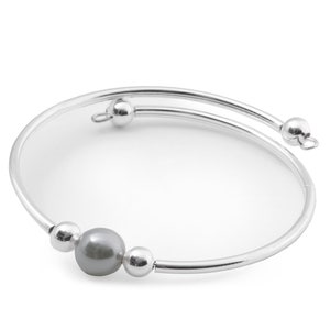 Puede incluir: Un brazalete de plata con una sola perla gris y cuentas de plata.