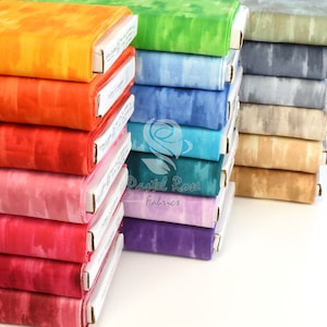 Könnte beinhalten: Ein Stapel bunter Stoffe mit einem Batik-Muster. Der Stoff ist in einem Regenbogen von Farben angeordnet, von Orange bis Lila. Der Stoff ist mit "Pastel Rose Fabrics" beschriftet.