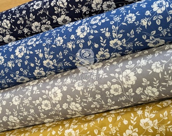 May include: Four rolls of fabric with a white floral pattern on a navy blue, blue, gray, and gold background.
