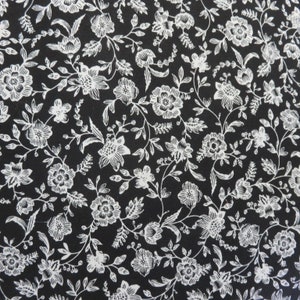 May include: Black fabric with a white floral pattern. The pattern features small flowers and leaves.