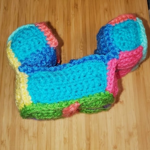 May include: A crocheted toy in the shape of a U with a bright blue, green, yellow, pink, and light blue color scheme.