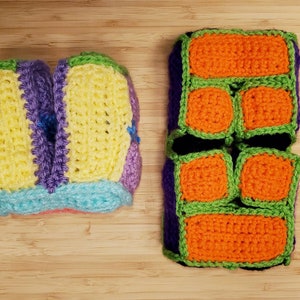 May include: Two crocheted tissue box covers. One is multi-colored with yellow, purple, blue, and pink. The other is black with green and orange squares.
