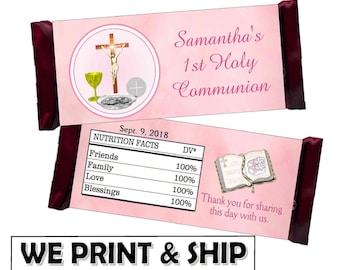 May include: Pink and white chocolate bar wrapper with a cross, chalice, and host on the front. The back of the wrapper has a Bible and the text "Samantha's 1st Holy Communion Sept. 9, 2018".