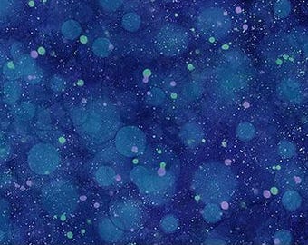 Op de afbeelding: Close-up van blauwe stof met een gespikkeld patroon. De stof heeft verschillende tinten blauw, met grotere cirkelvormige vormen en kleinere stippen van groen en paars. Een liniaal aan de onderkant toont de afmetingen in centimeters.