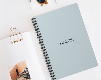 May include: A light blue spiral bound notebook with the word "notes." printed in black on the cover.
