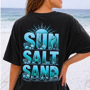 Puede incluir: Camiseta negra con un diseño gráfico turquesa con las palabras "SUN SALT SAND" e ilustraciones con temática oceánica. El diseño incluye un sol, un caballito de mar, conchas, estrellas de mar y palmeras.