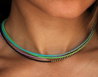 May include: A layered necklace with black, gold, purple, and green beads.