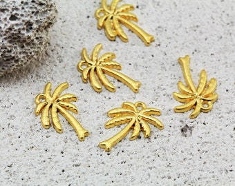 May include: Five gold palm tree charms, each with a different design, are scattered on a light gray textured surface.