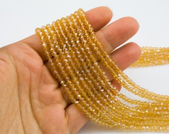 May include: A strand of golden yellow faceted glass beads. The beads are small and have a slight iridescent shimmer.
