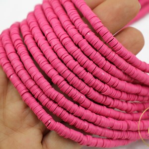 May include: A strand of pink polymer clay beads, each bead is a flat circle with a hole in the center. The beads are stacked on top of each other, creating a thick, colorful strand.