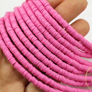 May include: A strand of pink polymer clay donut beads. The beads are approximately 1/2 inch in diameter and have a smooth, glossy finish.
