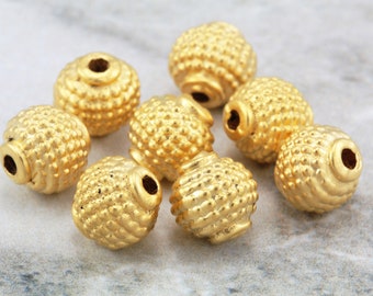 May include: A group of nine gold-colored metal beads with a textured surface. The beads are round and have a hole in the center.