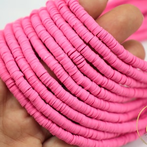 May include: A strand of pink polymer clay beads, each bead is a flat circle with a hole in the center. The beads are stacked on top of each other, creating a thick, colorful strand.