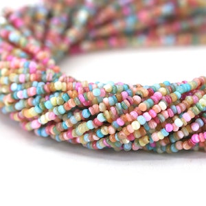 May include: A strand of colorful, small, round, and flat beads. The beads are made of a variety of materials, including shell, glass, and stone. The beads are strung on a clear thread and are arranged in a random pattern.