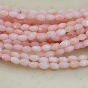 Può includere: Una collana di perline ovali rosa. Le perline hanno una lucentezza madreperlacea.