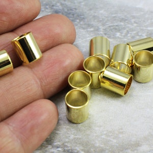 Puede incluir: Un grupo de 10 tapones de extremo de cable de metal de color dorado. Los tapones son cil&iacute;ndricos y tienen un acabado liso y brillante.