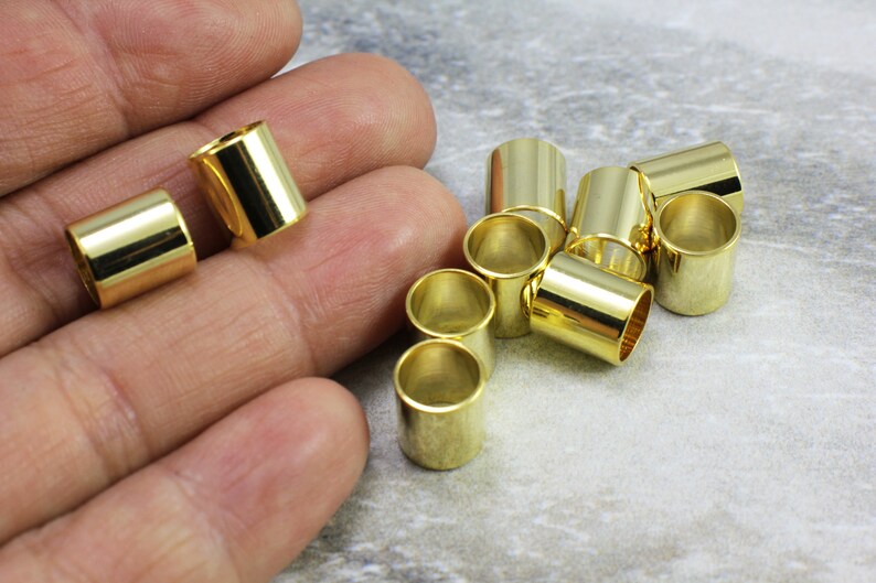 Puede incluir: Un grupo de 10 tapones de extremo de cable de metal de color dorado. Los tapones son cil&iacute;ndricos y tienen un acabado liso y brillante.