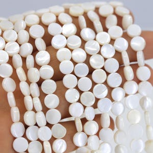 Puede incluir: Una hebra de cuentas redondas de concha blanca con un acabado nacarado iridiscente.