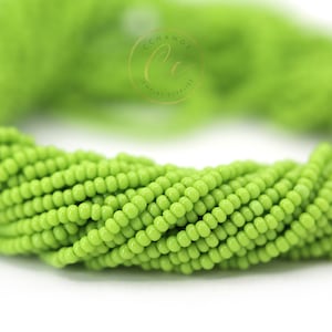 May include: A close-up of a strand of lime green seed beads. The beads are small and round, and they are arranged in a tight, twisted pattern.