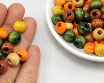 May include: A collection of wooden beads in various shades of green, orange, and brown. The beads are round and have a hole in the center. They are perfect for crafting projects.