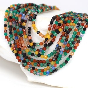 May include: A strand of colourful gemstone beads, including green, red, yellow, blue, and black. The beads are faceted and have a polished finish.