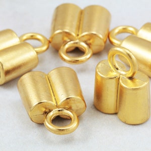 May include: Five gold-toned metal end caps for jewelry making. Each cap has two holes and a loop for attaching to a chain or cord.