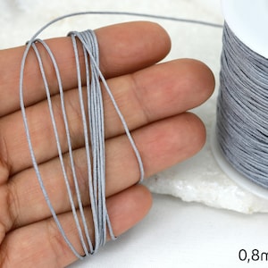 May include: A spool of grey elastic cord, 0.8mm thick, for jewellery making or crafts.