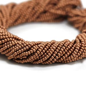 Könnte beinhalten: Eine Schnur kupferfarbener Perlen. Die Perlen sind klein und rund und zu einer engen Spirale angeordnet.