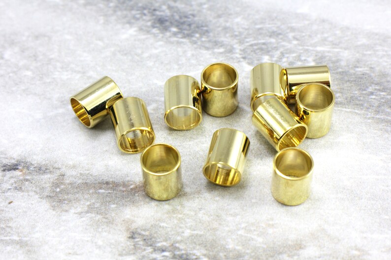 Puede incluir: Un grupo de 12 tapones de extremo de metal de color dorado para la elaboraci&oacute;n de joyas. Los tapones de extremo son cil&iacute;ndricos y tienen un acabado liso y brillante.