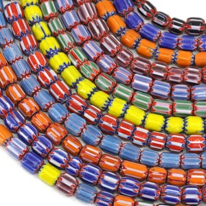 May include: A close-up of a collection of colourful glass beads. The beads are cylindrical and have a striped pattern. The colours of the beads include red, orange, yellow, green, blue, and white.