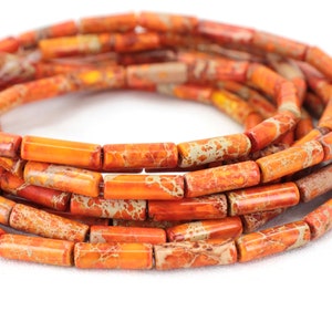 Puede incluir: Una hebra de cuentas de jaspe naranja y blanco, cada cuenta tiene forma de tubo rectangular.
