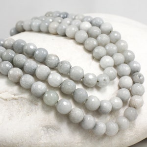 Peut inclure: Un brin de perles de pierres précieuses gris clair. Les perles sont rondes et ont une finition facetée.