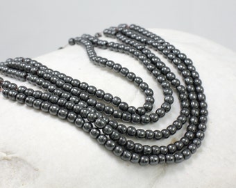 May include: A strand of black hematite beads, with a smooth, polished finish. The beads are round and uniform in size, and they are strung on a thin wire.