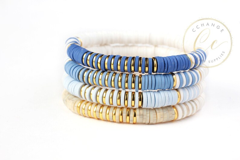 May include: Four stacked bracelets with blue, white, and gold beads. The bracelets are made of ceramic and have a graduated color scheme, starting with a dark blue and fading to white.