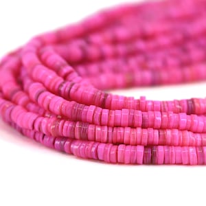 May include: A strand of pink shell beads, each bead is a flat, round disc with a slightly irregular shape.