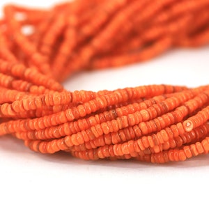 Peut inclure: Un brin de perles de corail orange. Les perles sont petites et rondes, et elles sont enfilées sur un cordon fin.