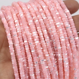 May include: Strands of pink, square-shaped beads. The beads have a subtle iridescent sheen, with hints of white and silver. The beads are strung together, creating a delicate and feminine aesthetic. Ideal for jewelry making.