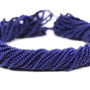 May include: A strand of dark blue seed beads, arranged in a circular shape.