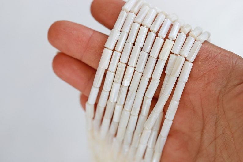 Pu&ograve; includere: Una collana di perline bianche di conchiglia, ogni perlina ha la forma di un tubo rettangolare.