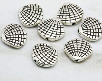 May include: Eight silver-toned metal beads shaped like seashells with a textured surface. The beads have a hole in the center for stringing.