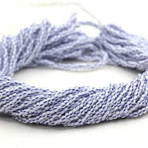 May include: A strand of white glass beads with blue stripes. The beads are small and round, and they are strung together on a thin thread.