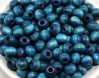 May include: A bowl filled with teal blue wooden beads. The beads have a hole through the center for stringing.