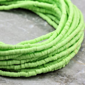 May include: A strand of light green polymer clay beads. The beads are small and round, and they are strung together in a long strand. The beads are perfect for making jewelry or other crafts.