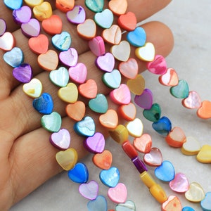 May include: A strand of colorful heart-shaped beads made from iridescent mother of pearl. The beads are strung on a clear elastic cord and are perfect for making jewelry.